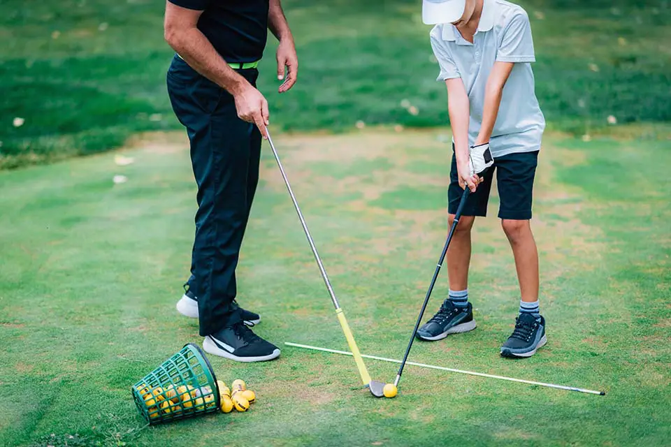Golf Instructor Teaching Young Boy How to Play Golf